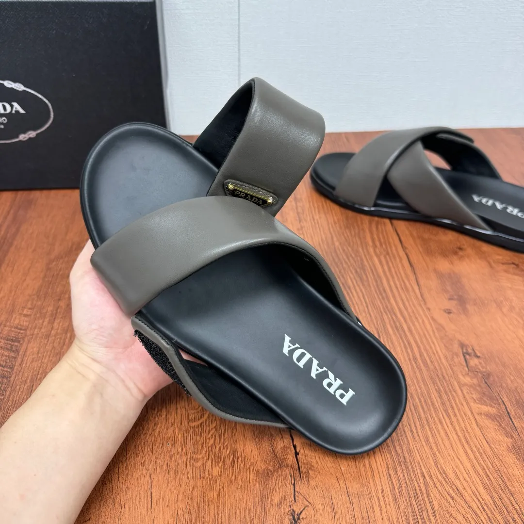 Batch 580 Prada/Prada's new men's leather cross slippers. Velcro closure can finely adjust the size. Calf leather light luxury slippers. Thick soft calf leather wraps the upper. Fat but soft rubber lazy style, soft and comfortable, excellent foot feel. Genuine leather bottom layer, cross style, with a Velcro closure buckle, easy to adjust the appropriate size, and a perfect fit for the wearing experience. The enamel gold triangle logo highlights the brand's classic features. Lightweight rubber thin sole, high foot comfort! Complete package! Size: 39-40-41-42-43-44-45 Leather shoe size Item number: 2X7132 Gray